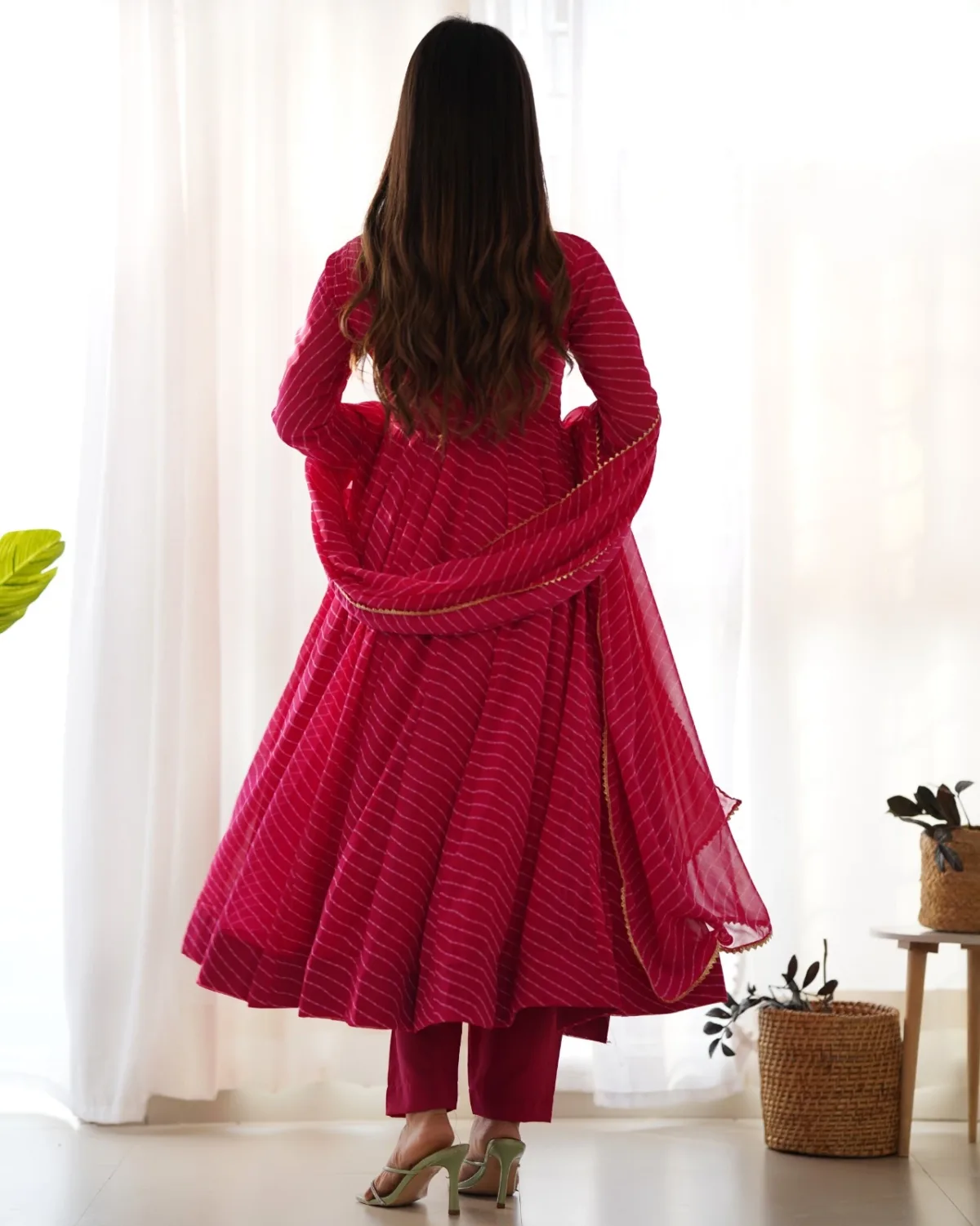 Back view of rani pink flared Anarkali suit set with matching pants and dupatta featuring elegant ethnic design.