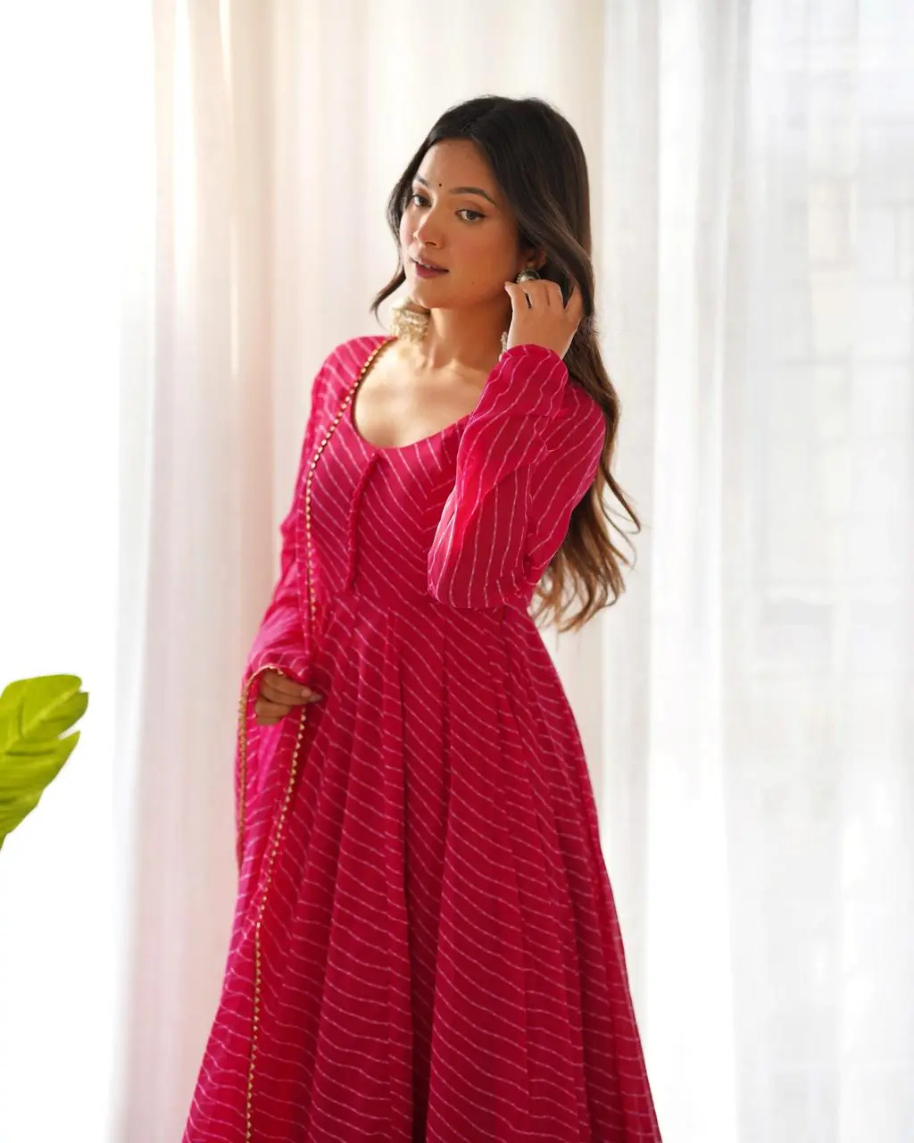Women's Rani Pink Leheriya Printed Anarkali Suit Set with Dupatta Front View Woman wearing a rani pink leheriya printed Anarkali kurta with matching pants and dupatta, front side view ethnic festive wear suit set.